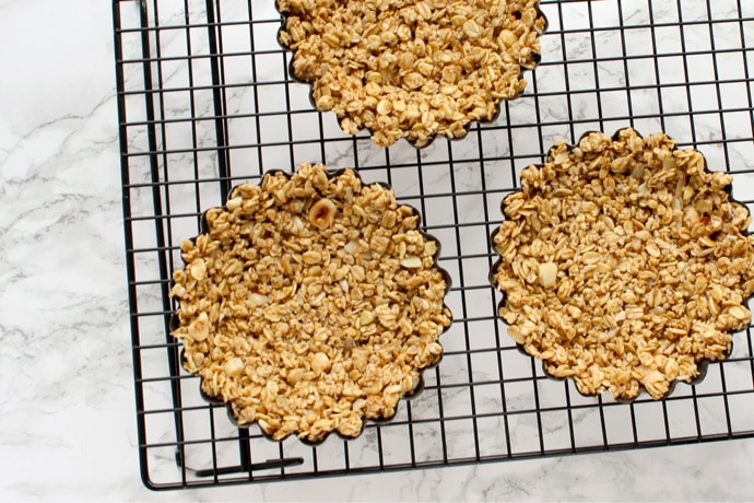 three granola tart bases in their tart baking moulds.