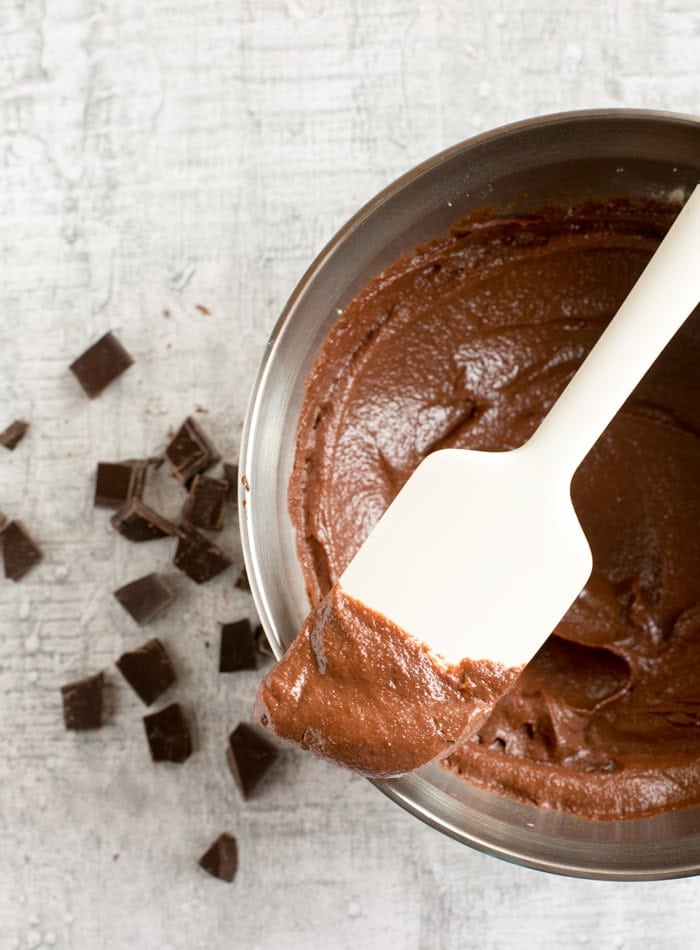 chocolate frosting on a white spatula over a bowl of chocolate frosting