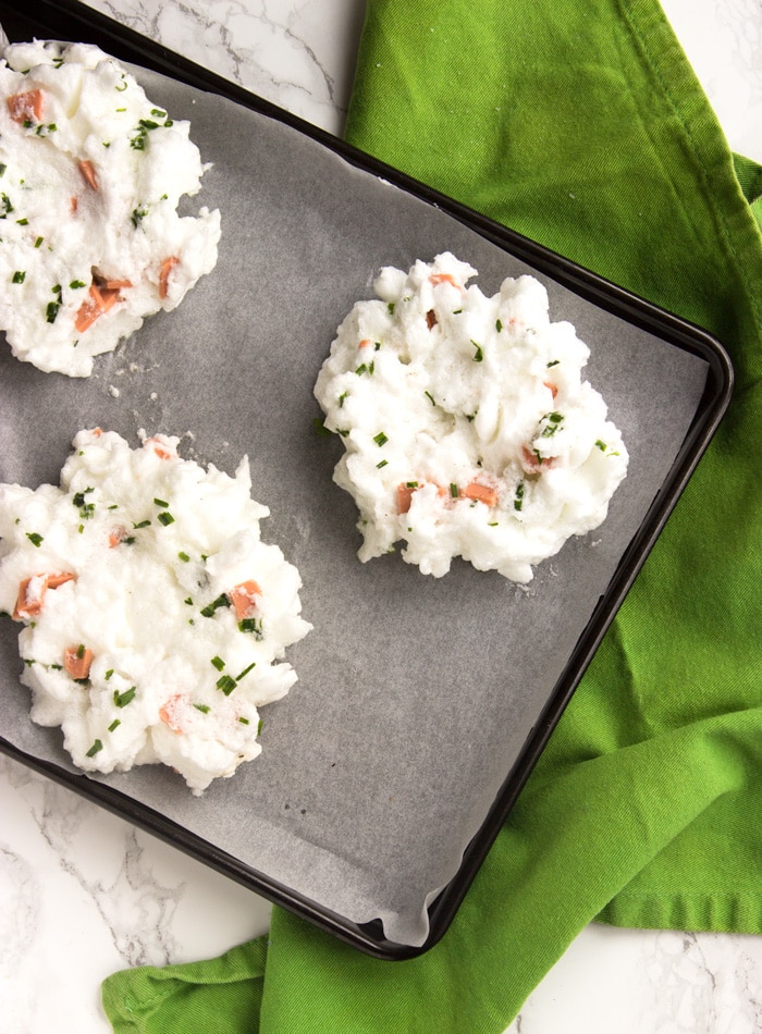 eggs in a cloud mixture divided in three clouds over a baking tray covered with parchment paper, over a green napkin