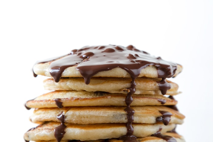 stack of american pancakes topped with chocolate sauce