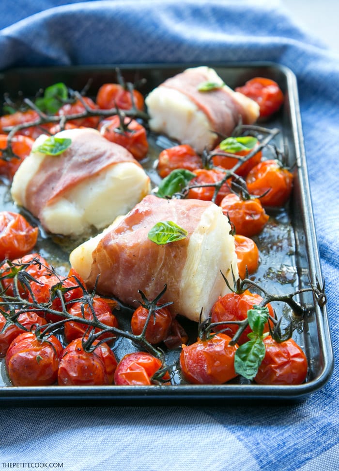 Make dinner time easy with this Prosciutto Wrapped Cod with Roasted Tomatoes - A one-tray easy italian-style meal, gluten-free, dairy-free and ready in just 20 min! Recipe by The Petite Cook - www.thepetitecook.com