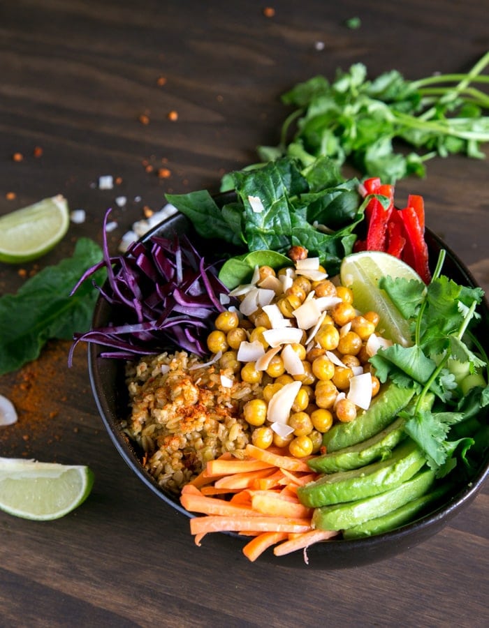 chickpea and freekeh buddah bowl with sliced avocado and carrots and salad leaves.