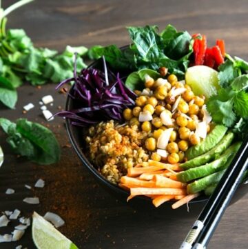 chickpea and freekeh buddah bowl with sliced avocado and carrots and salad leaves.