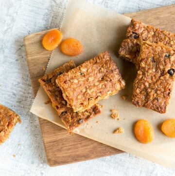 Vegan fruit flapjacks on a wood board covered with parchement paper, dried apricots on the left