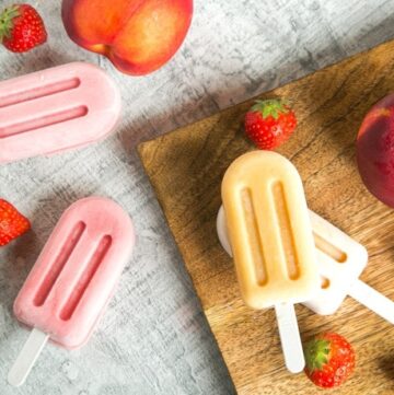 Nectarine and Strawberry Smoothie Popsicles, two on wood plate next to a nextarine and strawberries, two on grey background next to 2 strawberries and another nectarine