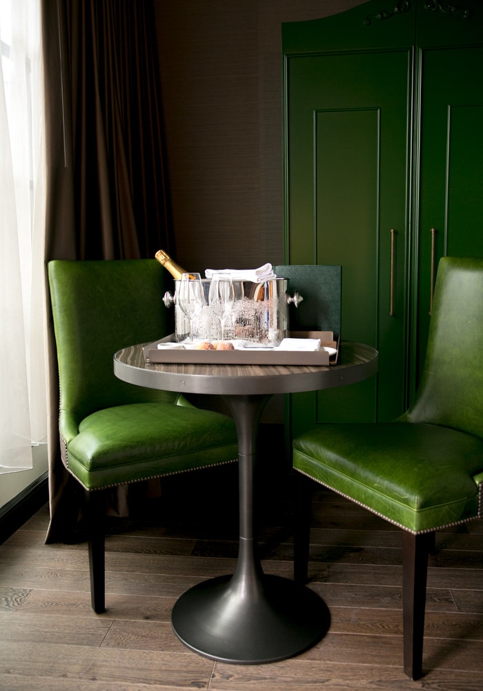 green chair and small table with tray two glasses and champagne in a ice bucket