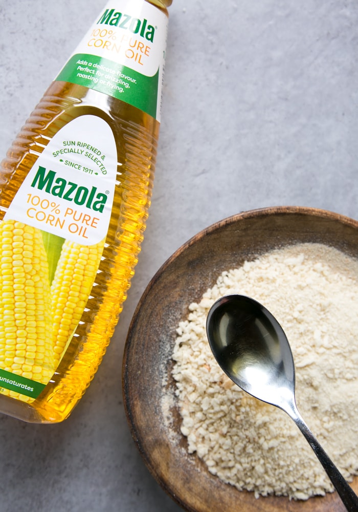 mazola oil bottle, oil in a spoon and panko breadcrumbs on a plate