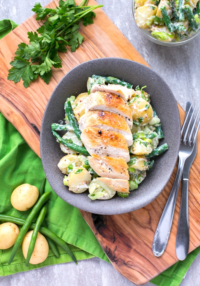 Grilled chicken breast with potato salad and green beans.