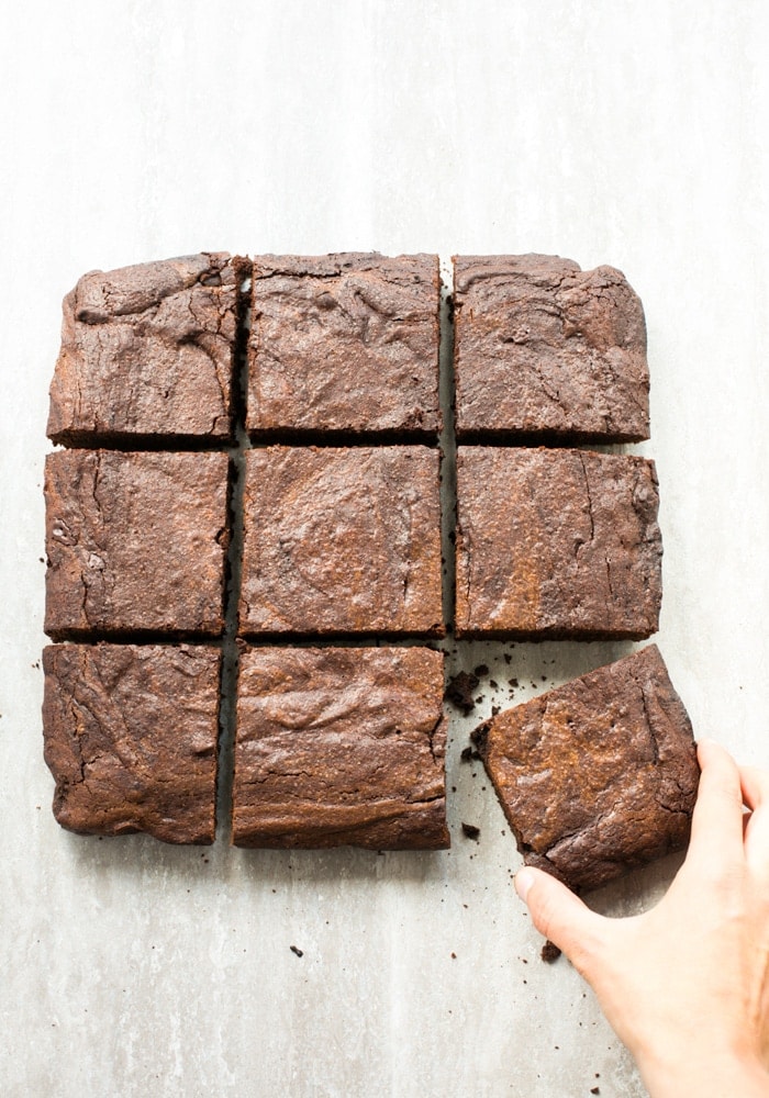 espresso brownies cut into squares, hand holding a brownie on the left down side of the picture