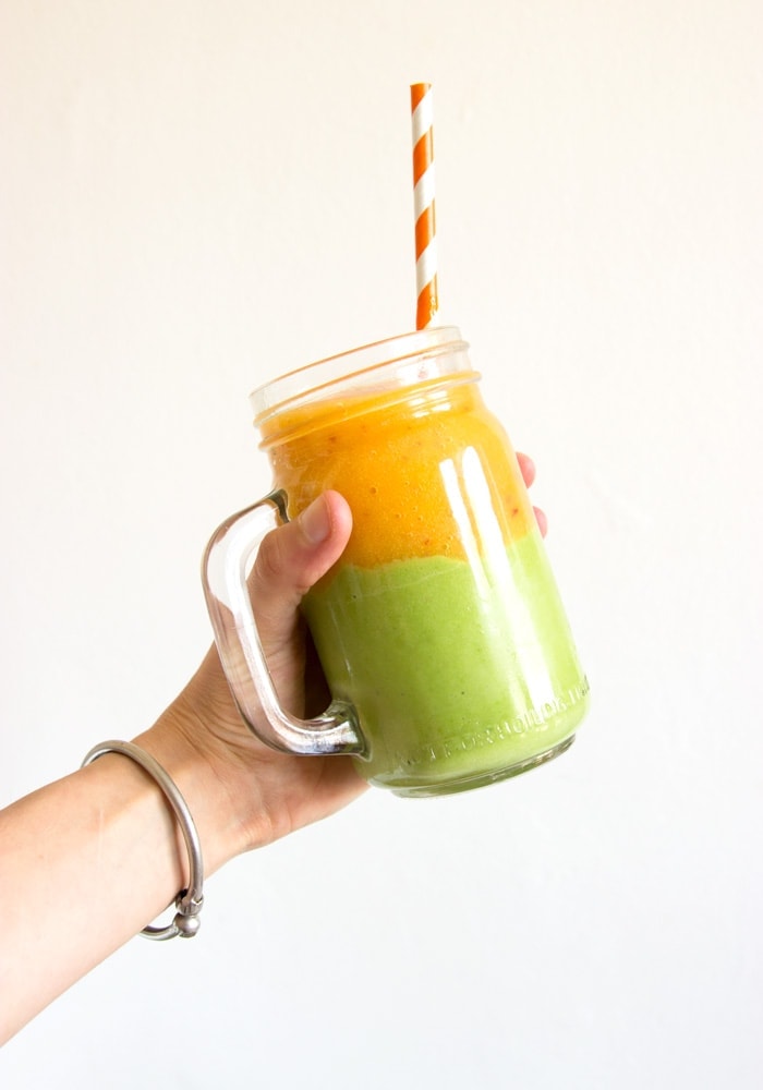 hand holding drinking jar with nectarine and avocado smoothie, topped with a straw