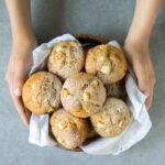 peach muffins in a wood bowl covered with a white napkin, held by two hands