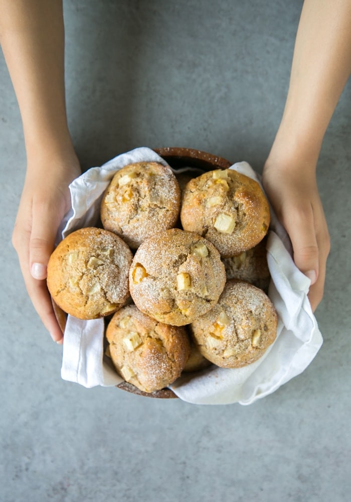 hands holding a bowl of peach muffins