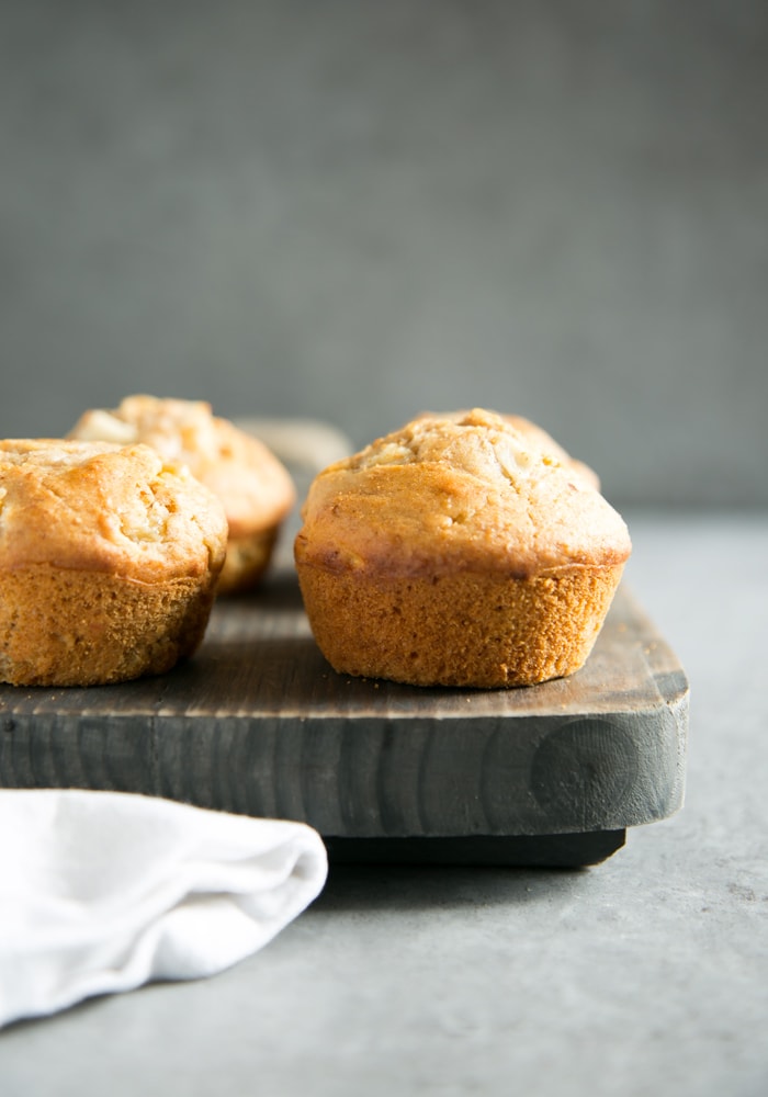 peach muffins on a wood board and white napkin on the left side