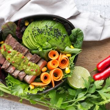 steak salad bowl with carrot, salad leaves,Avocado, steak topped with chimichurri sauce