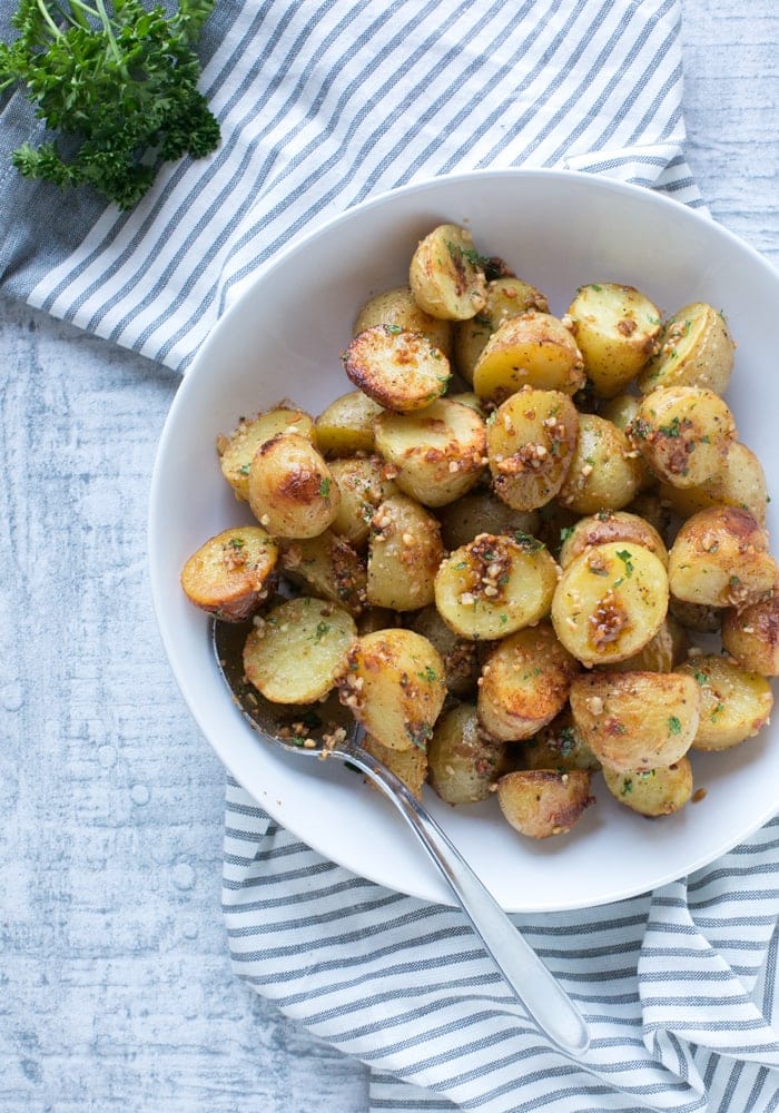 truffle pesto roasted potatoes on a white plate with a serving spoon