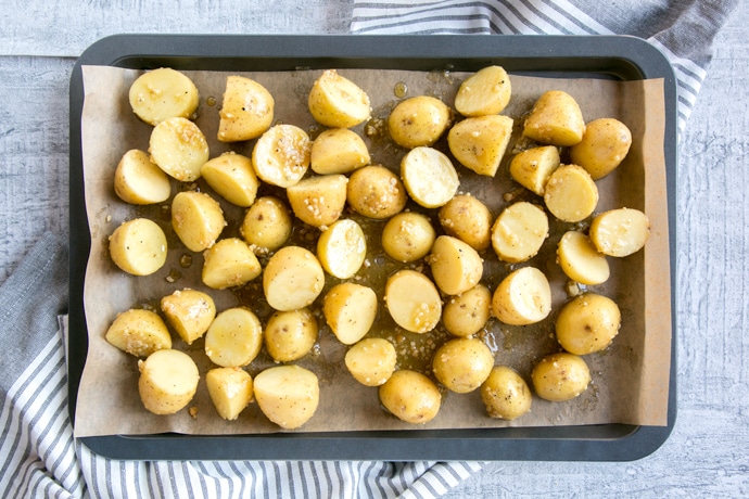 recipe step 1: new potatoes with olive oil and pesto on a baking sheet