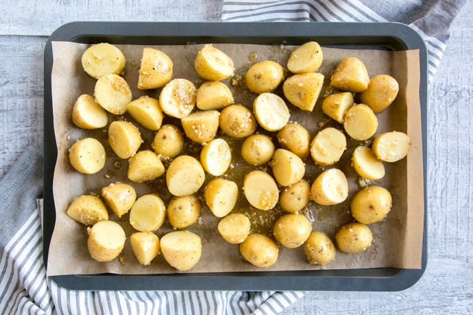 recipe step 1: new potatoes with olive oil and pesto on a baking sheet
