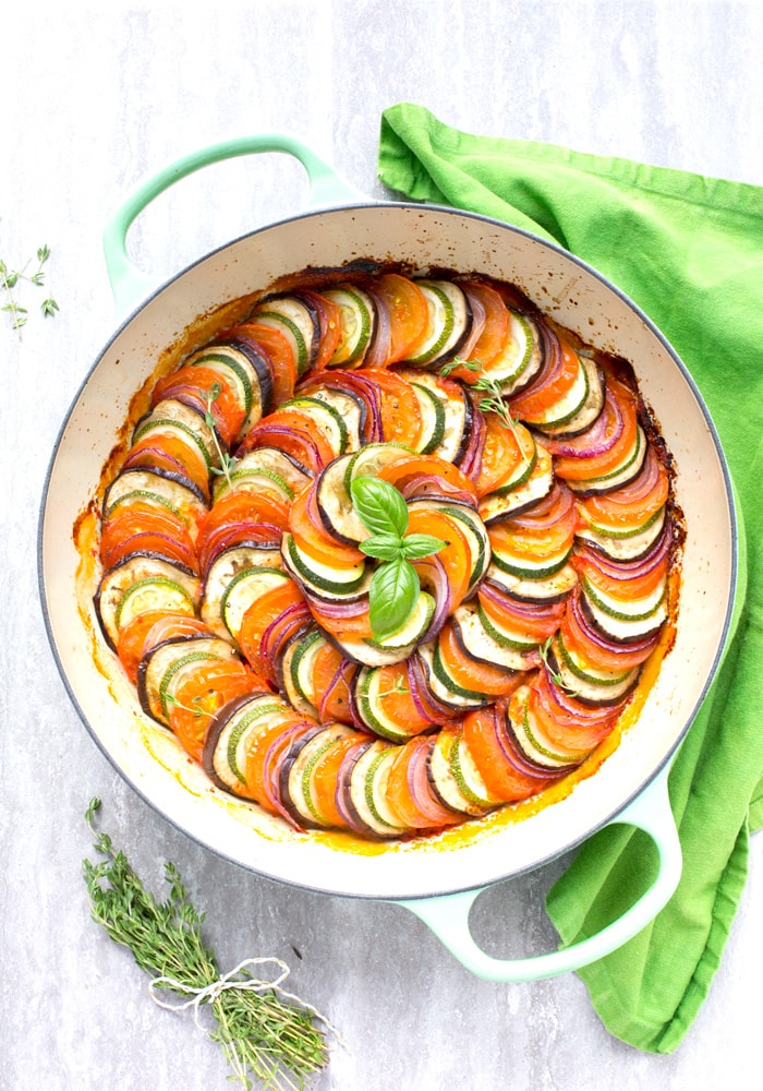 Easy Ratatouille in a large green cast iron shallow pan, bunch of thyme sprigs on the left side and a green napkin on the top right side.
