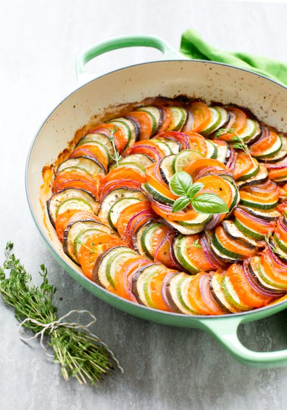 ratatouille in a cast iron shallow pot, topped with basil leaves.