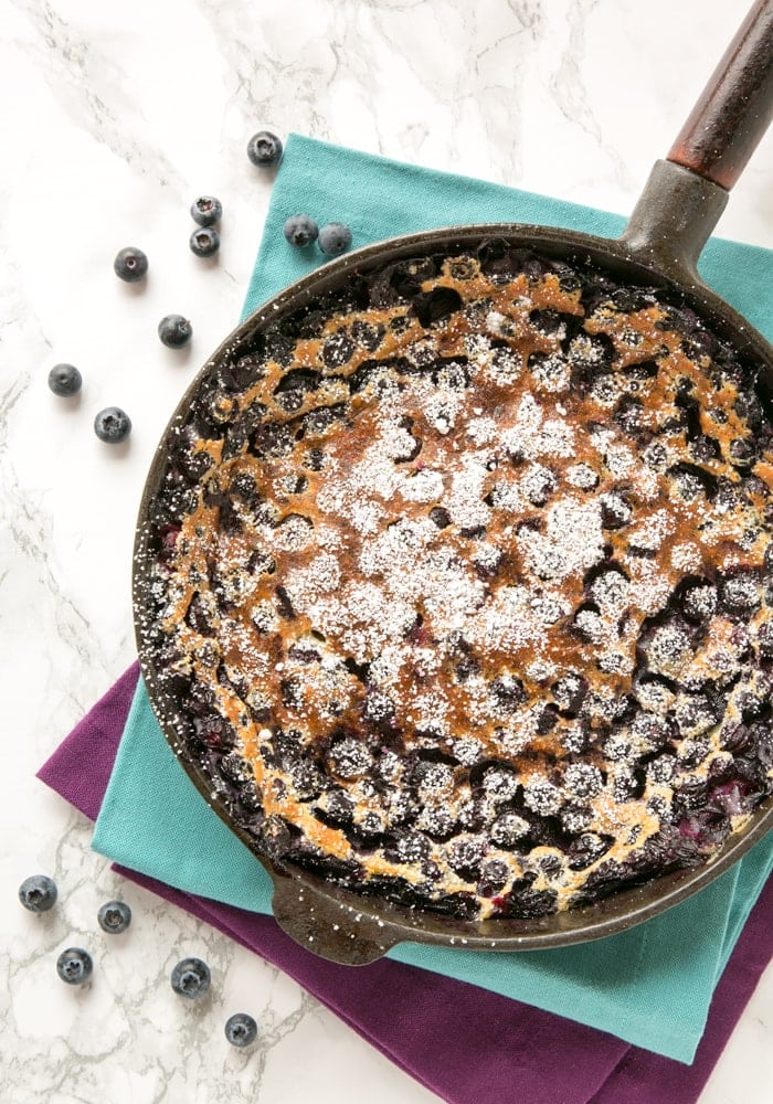 french blueberry clafoutis in a cast-iron skillet over two cloth napkins.