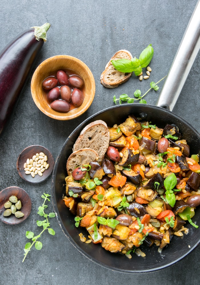 Aubergine Caponata in a skillet with bread on the side.