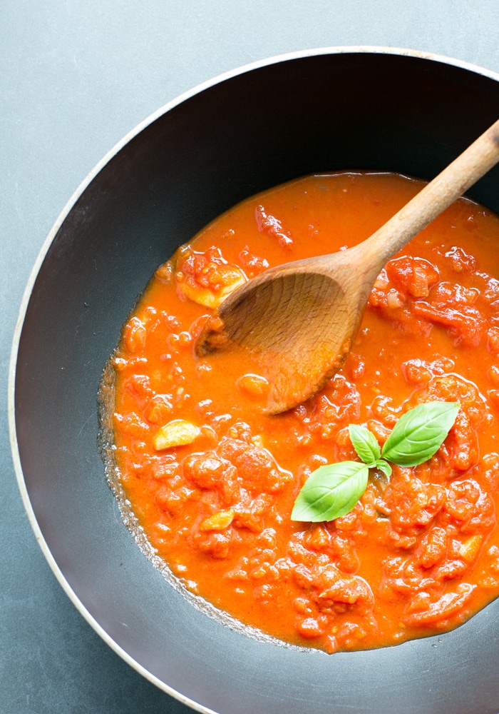 italian tomato sauce in a pan with a wooden spoon.