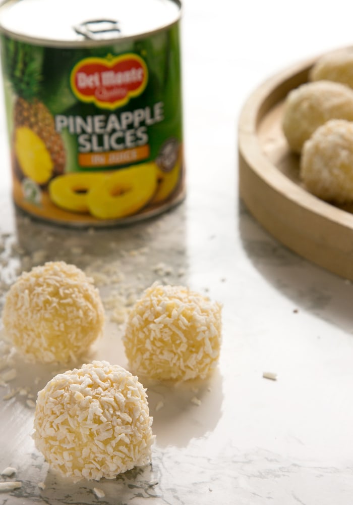 three pinapple ladoo, a can of pineapple slices in the background