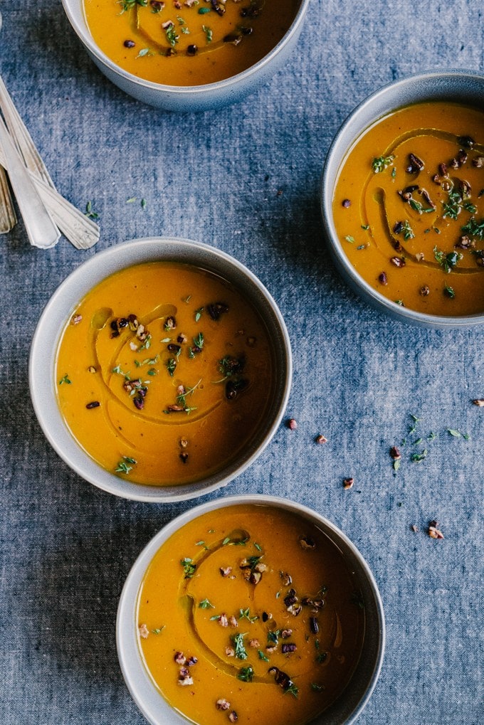 Roasted Carrot and Apple Soup in 4 bowls, on a blue background