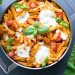 caprese pasta bake in a large baking pan, topped with mozzarella and basil leaves