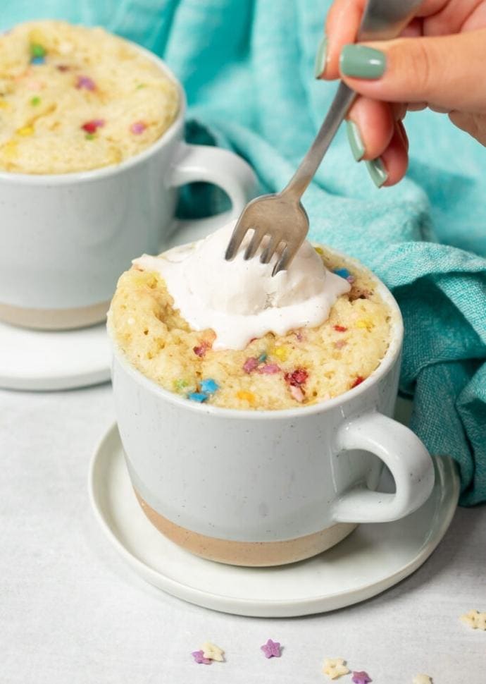 vegan vanilla mug cake topped with cream.