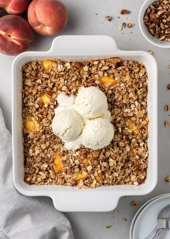 vegan peach crisp topped with vanilla ice cream.