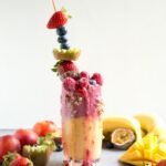 fruit freakshake in a glass topped with fresh fruit and mixed fruits all around