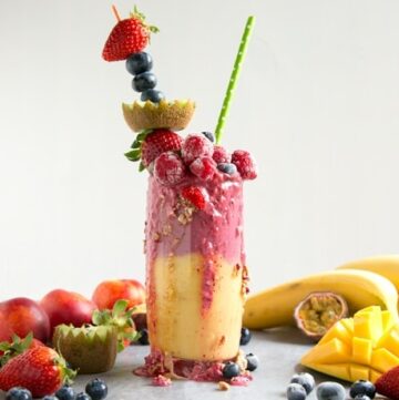 fruit freakshake in a glass topped with fresh fruit and mixed fruits all around