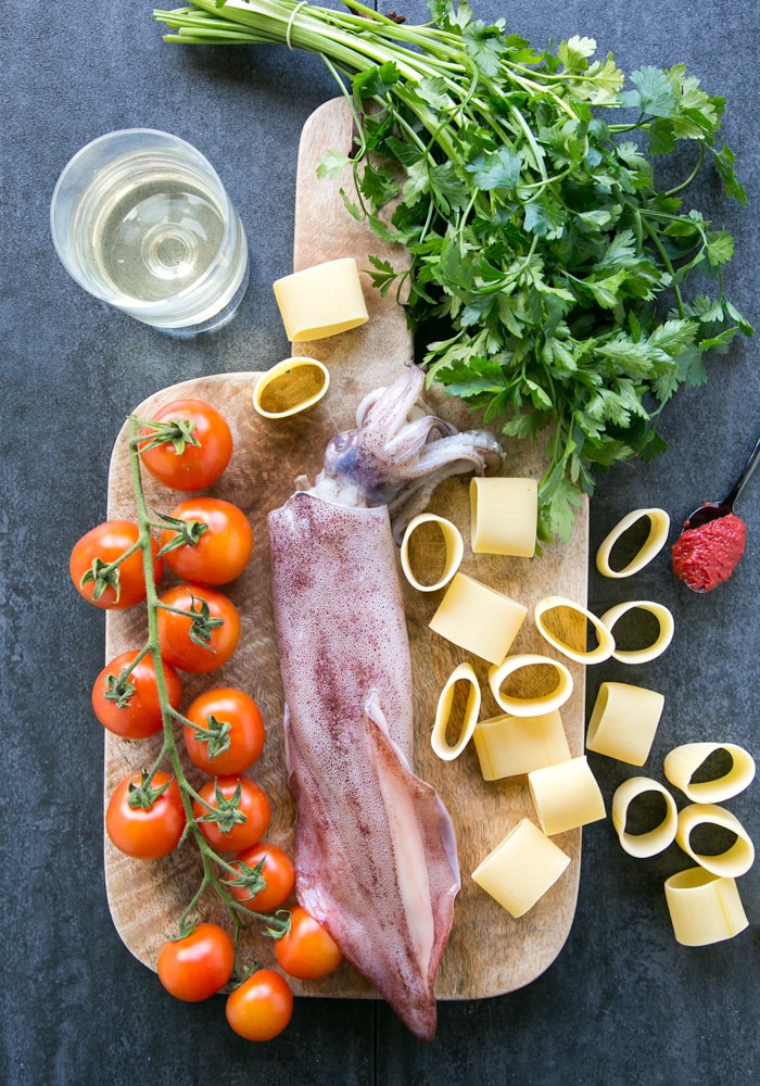 fresh calamari, cherry tomatoes, calamarata pasta, parsley, tomato pasta and glass of wine