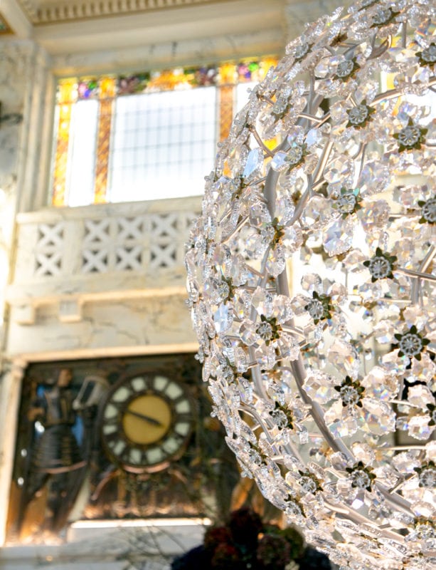 crystal flowers ball lamp with marble wall and clock in the background, interiors of the park hyatt vienna the bank resturant 