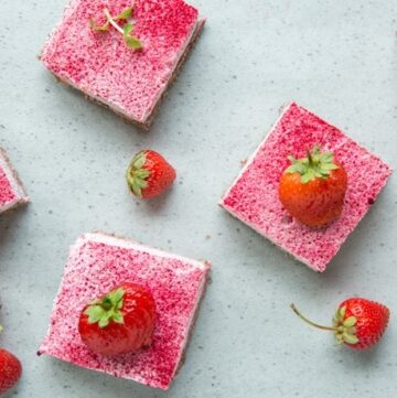 strawberry cheesecake bars and fresh strawberries on grey background