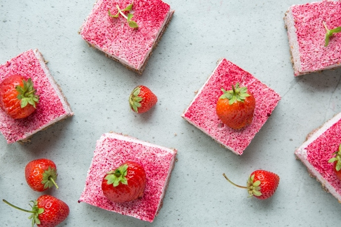 strawberry cheesecake bars and fresh strawberries on grey background