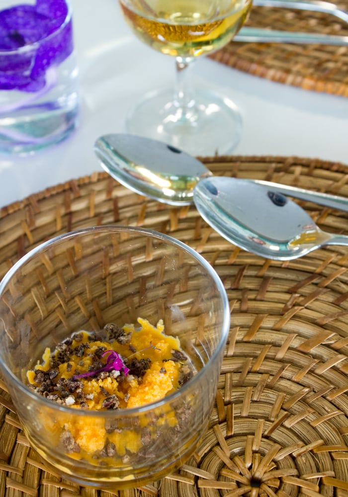 orchata granita and cocoa nibs in glass pot, spoons and wine glass in the background