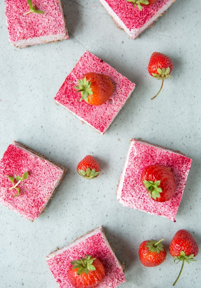 strawberry cheesecake bars and fresh strawberries on grey background