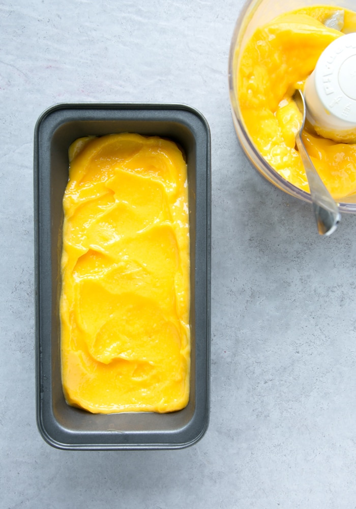 vegan mango sorbet in ice cream container on the left and in the bowl of a food processor with a spoon on the right