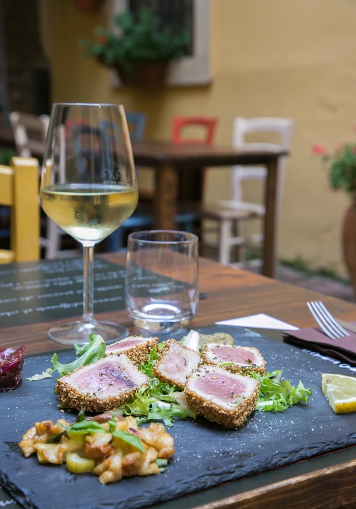 albacore tuna fillet in sesame crust, glass of white wine and restaurant background