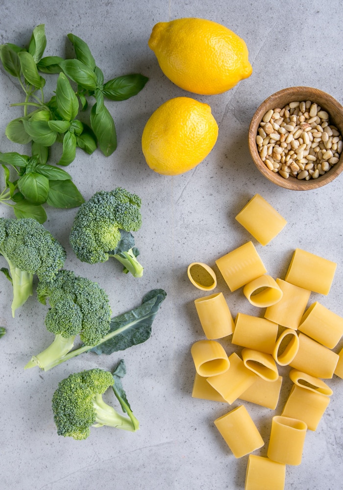 broccoli, basil, lemons, paccheri pasta and toasted pine nuts on grey board