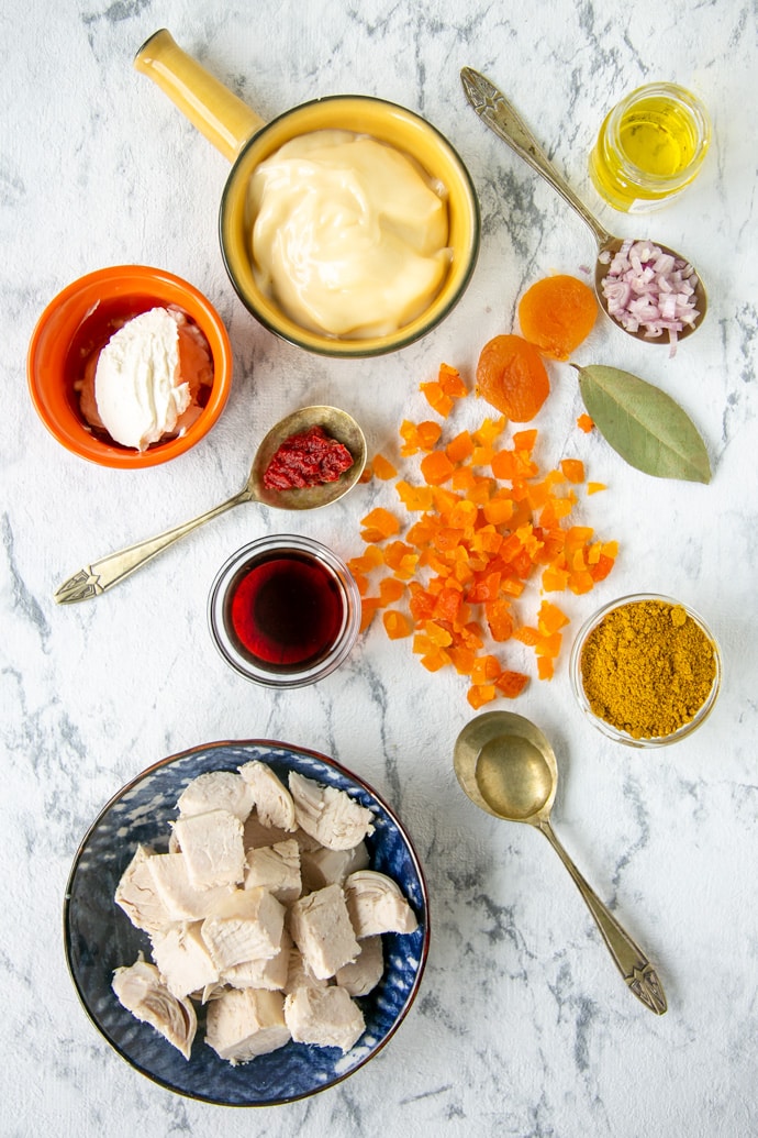 ingredients on a marble board: cooked chicken dried apricots mayonnaise crème fraîche olive oil curry powder white onion (or shallot) red wine bay leaf lemon juice a pinch of sugar salt & pepper