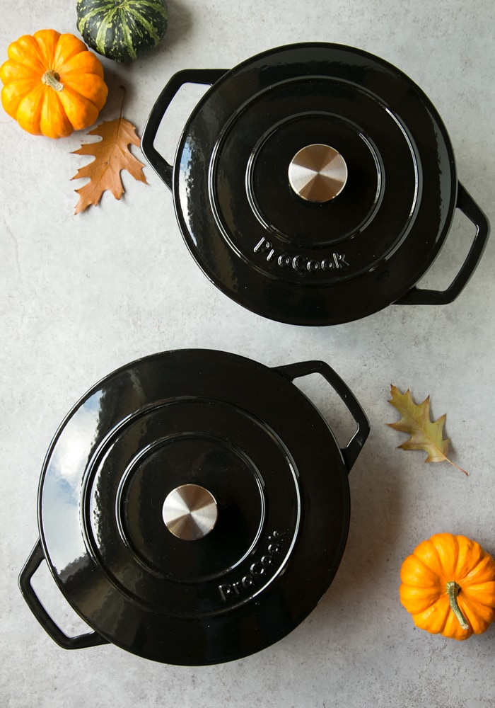 ProCook black cast iron casserole set, mini pumpkins and autumn leaves on the background