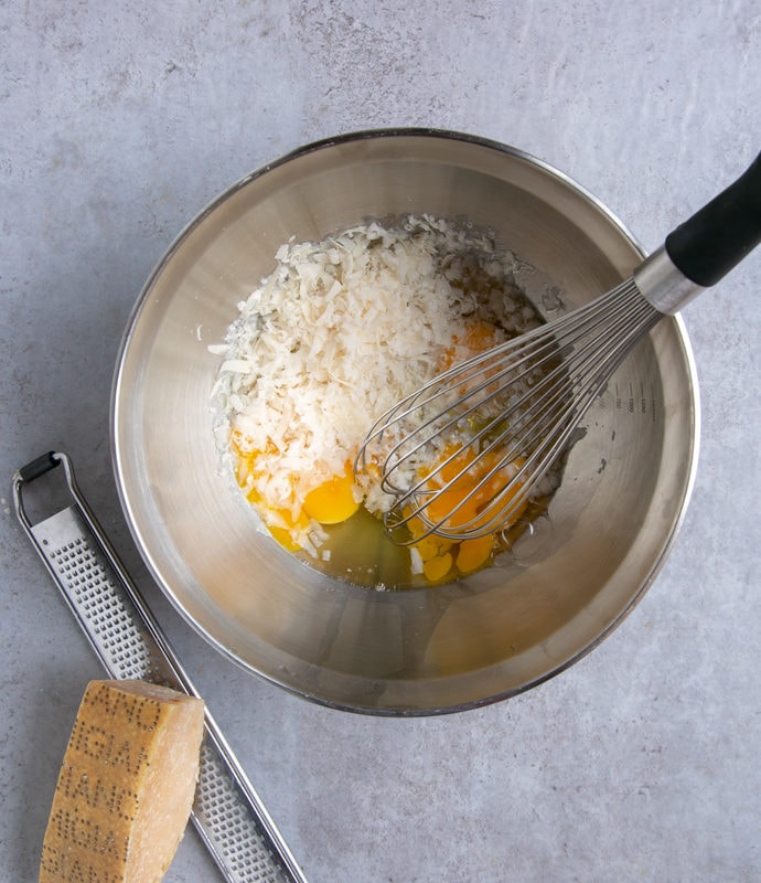 italian frittata with spinach and peas preparation step 2: eggs, grated parmesan and whisk in a large metal bowl, grater and parmesan piece next to the bowl