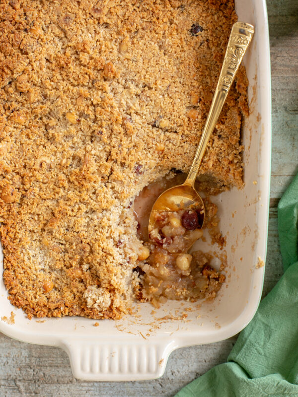 vegan apple crumble in a baking dish with golden spoon, a green napkin on the side