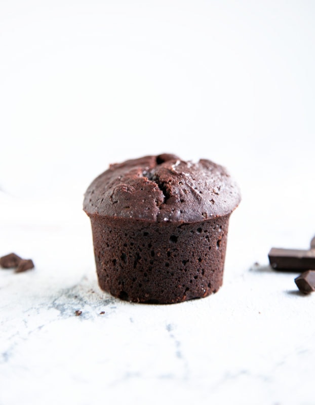 vegan chocolate muffin in a white background, dark chocolate chunks in the background
