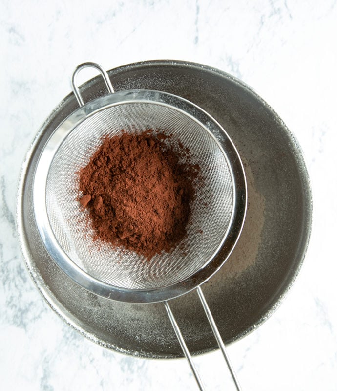 muffins recipe step 2: cocoa powder in sifter over metal bowl