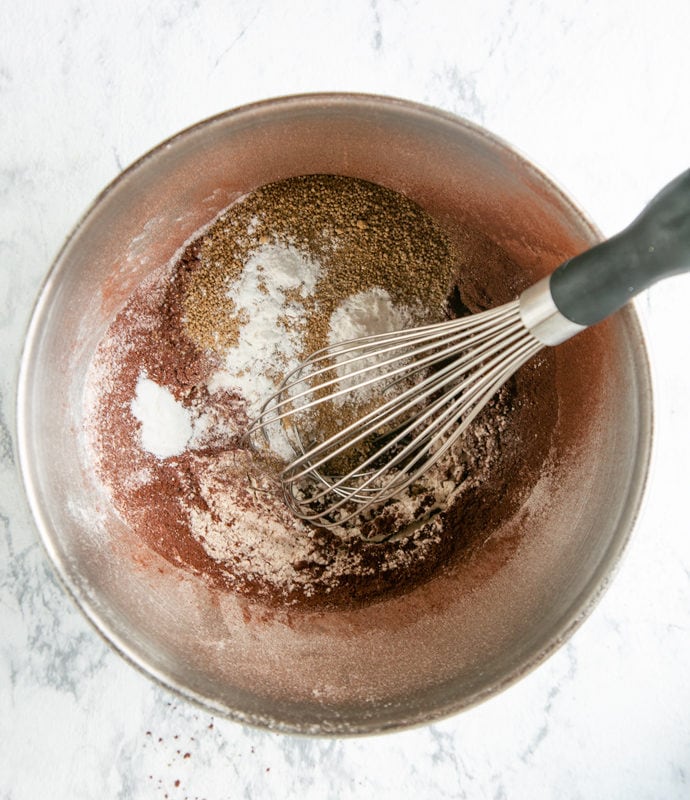 muffins recipe step 3: flour, cocoa powder, brown sugar, baking powder and olive oil in metal bowl and whisker