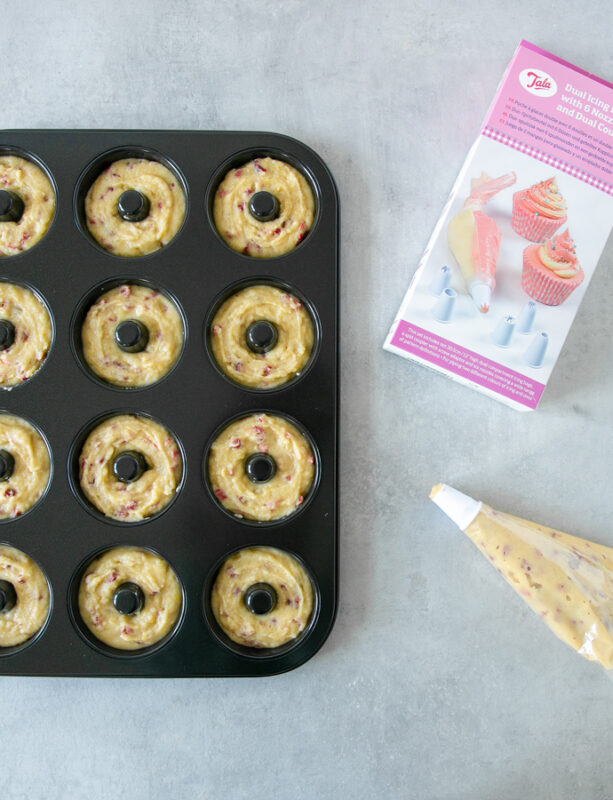 doughnut pan filled with batter, next to a piping bag filled with batter and Tala box of the piping bag